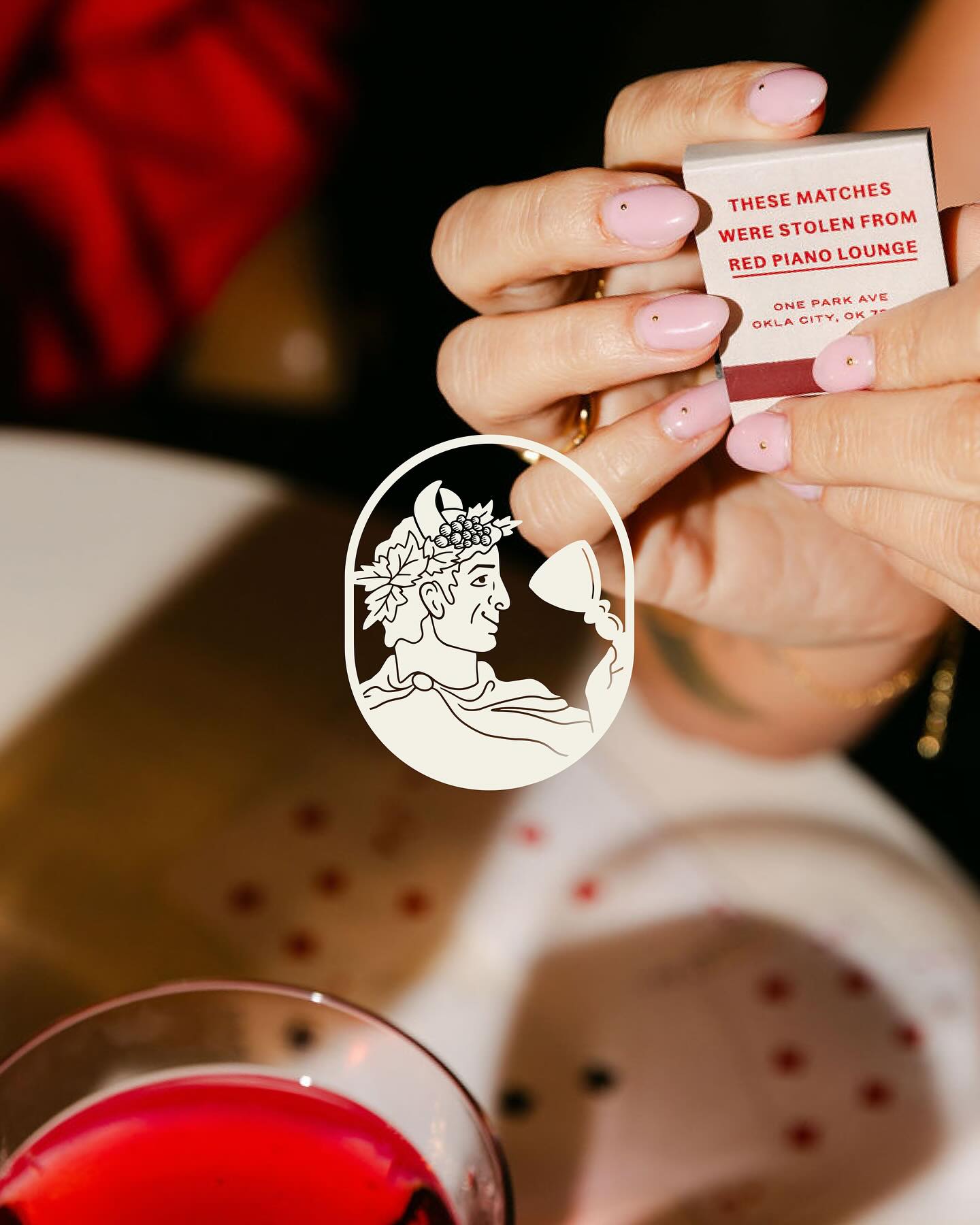 Red Piano Lounge matchbook held above a cocktail at the Skirvin Hilton
